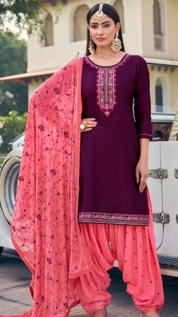 Woman in a traditional outfit with a pink dupatta standing in front of a vintage car.