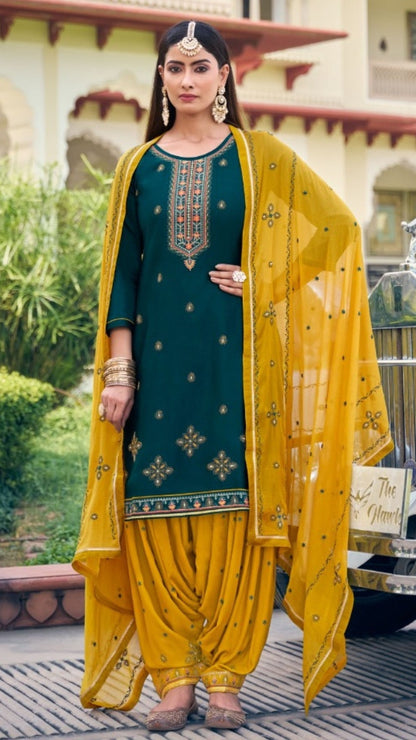 Woman in traditional green and yellow outfit standing outdoors with a building and car in the background