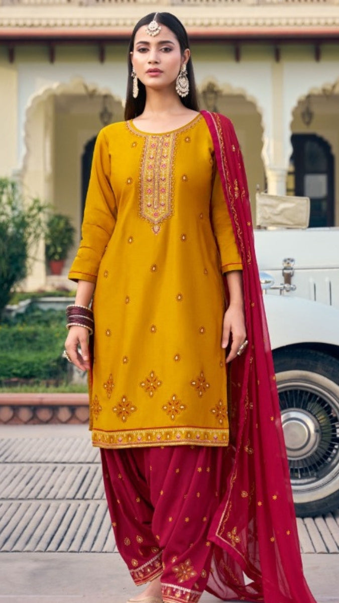 Woman in traditional yellow and red outfit standing in front of a building.