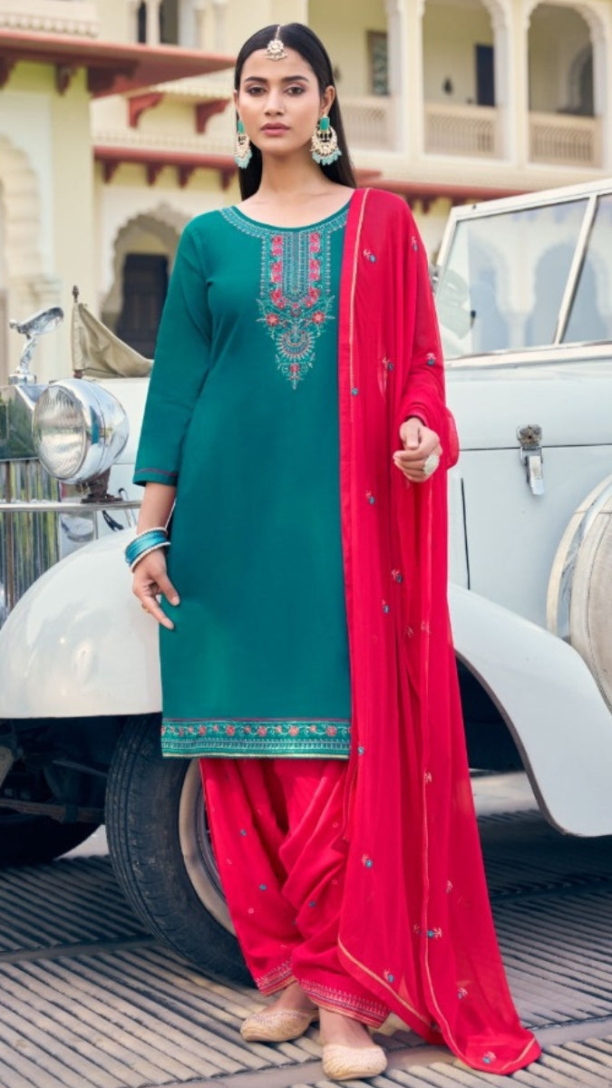 Woman in teal and red traditional outfit standing in front of a vintage car.