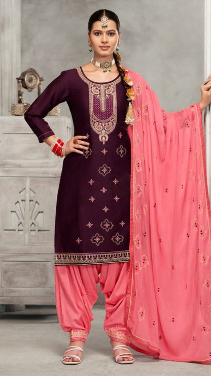 Woman wearing a traditional outfit with a purple top and pink dupatta in a neutral setting