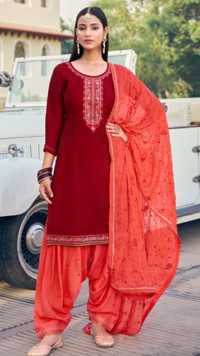 Woman in a red traditional outfit standing in front of a vintage car.